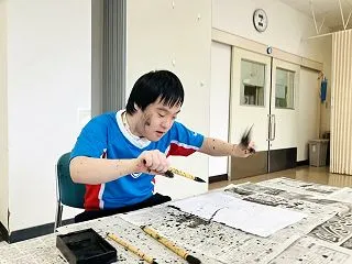 顔にも墨がバッチリつく息子の書道