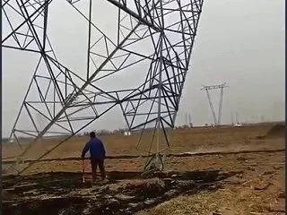 倒れていく送電鉄塔の足元を歩く男性に「お…