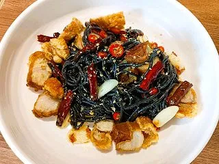 黒い麺にカリッと揚げた豚肉：Steak …