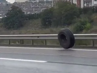 高速道路を車と並んで転がる野良タイヤ、大…